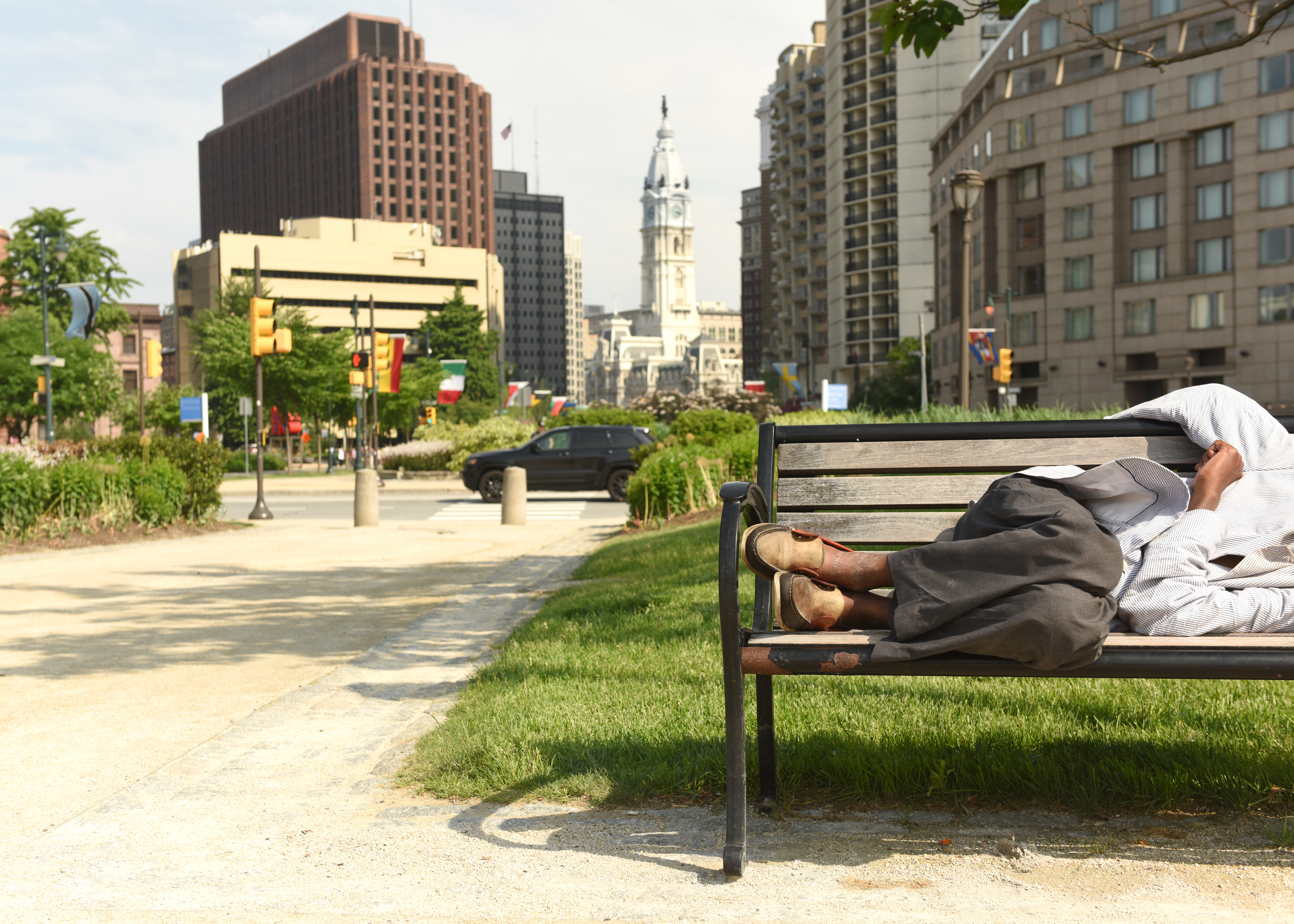 A man without housing sleeping on a park bench