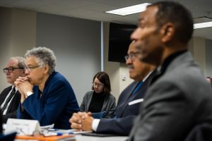 Five individuals pictured at a public meeting
